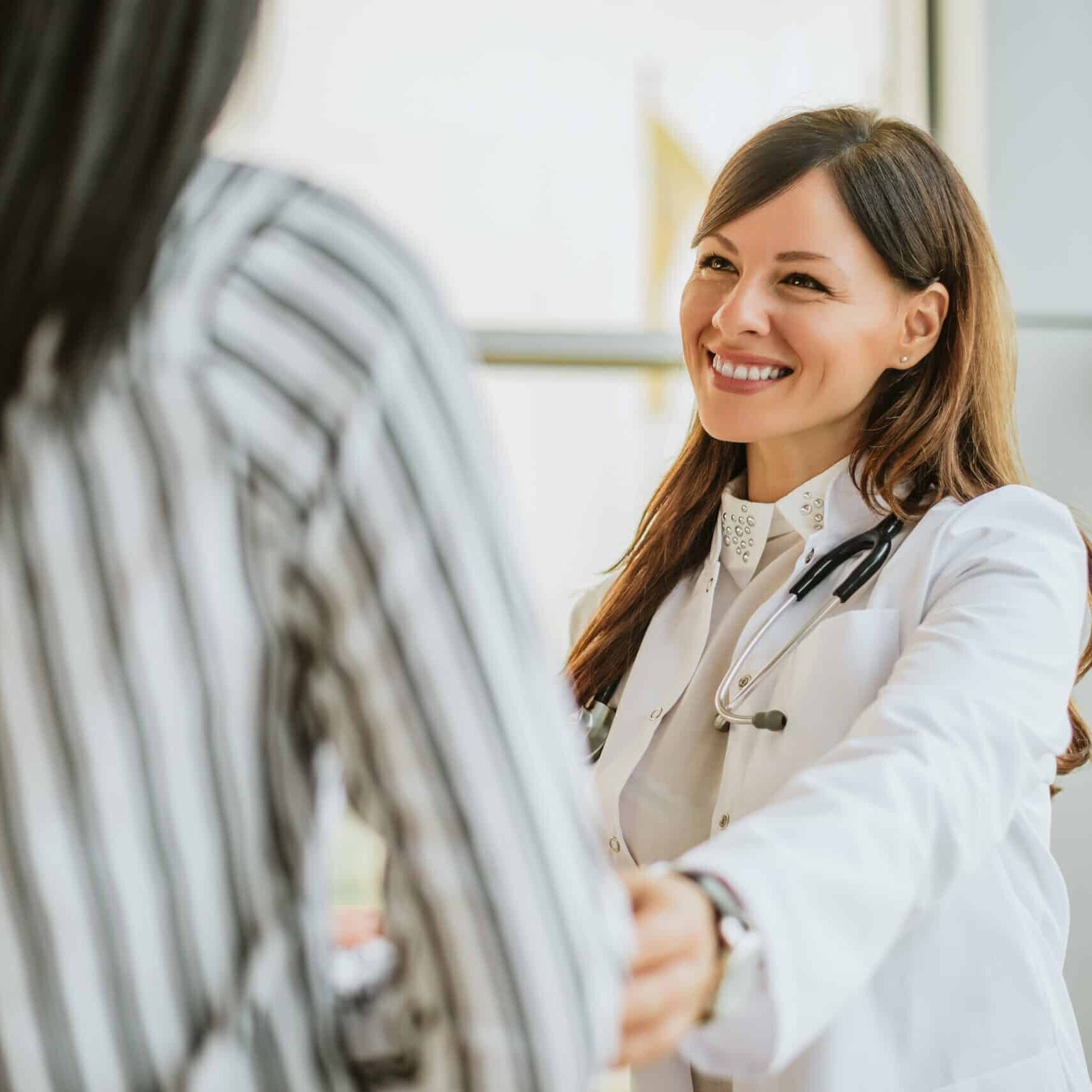 Female doctor talking and touching woman patient for encouragement.