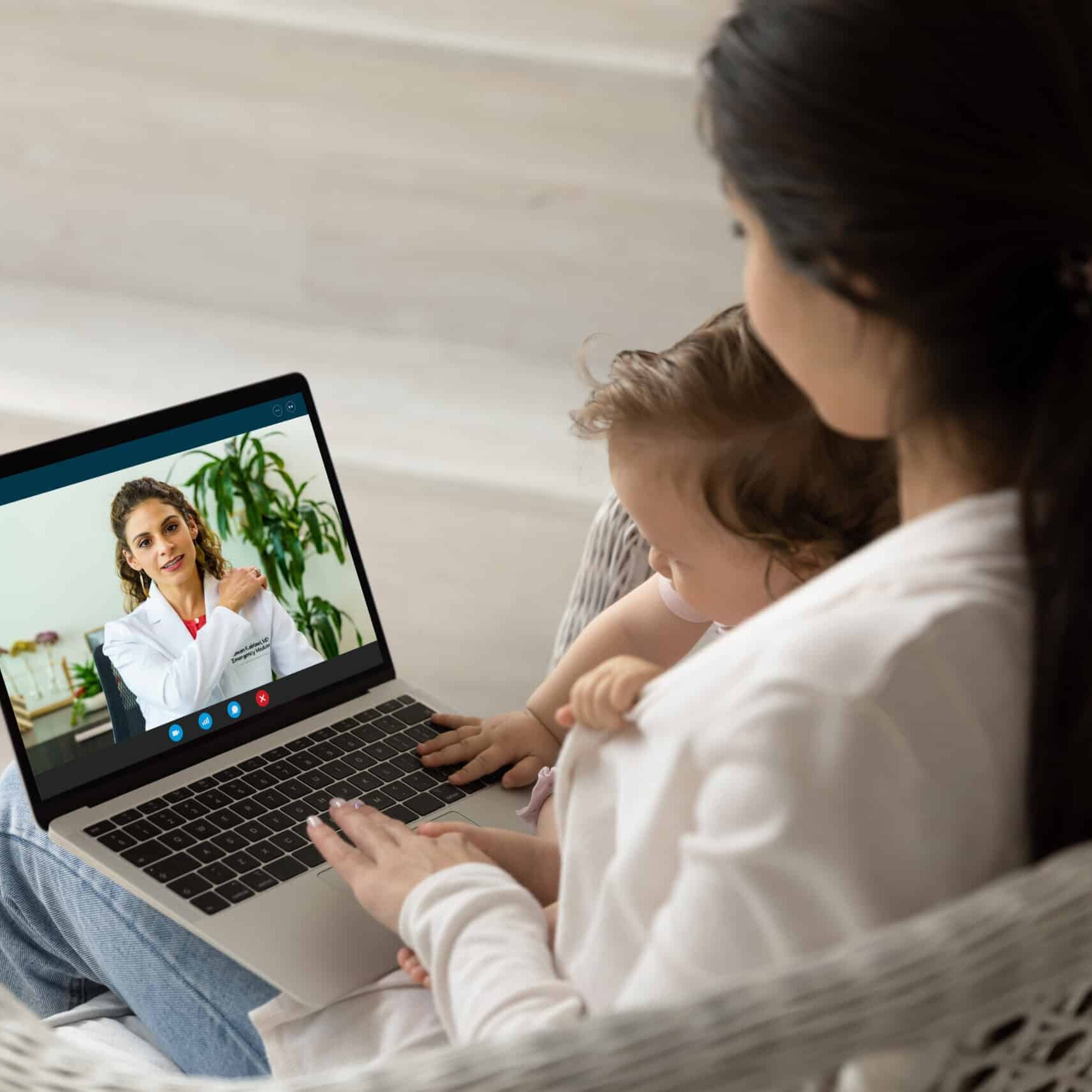 Loving mother hugging holding baby little daughter, using laptop, making video call to female pediatrician at home, doctor consulting caring mom online, telemedicine and children healthcare concept